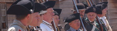 Clean shaven faces of 3rd NY soldiers stand in a line, muskets rest on thier left shoulder, and black cocked hats rest on thier heads.